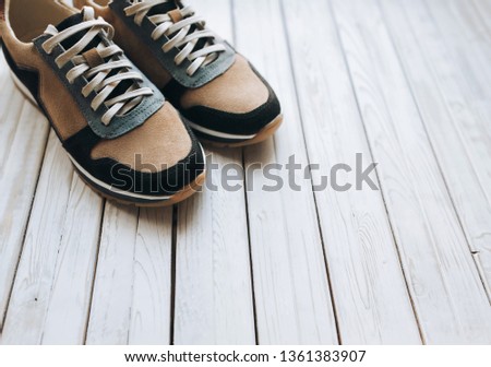 A pair of suede sneakers on a rustic wooden background. The concept of jog and sports shoes.