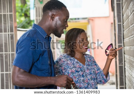 Happy couple standing in front of the shop window during shopping. woman pointing the window or a place