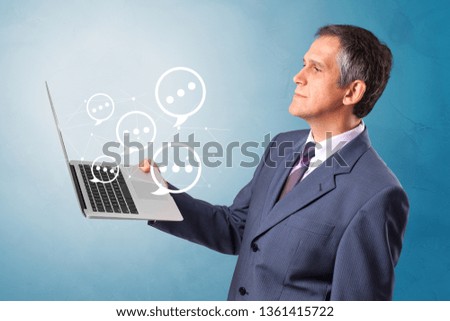 Man holding laptop with a few speech bubble symbols