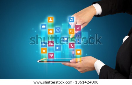 Female elegant hand holding tablet with colourful application icons