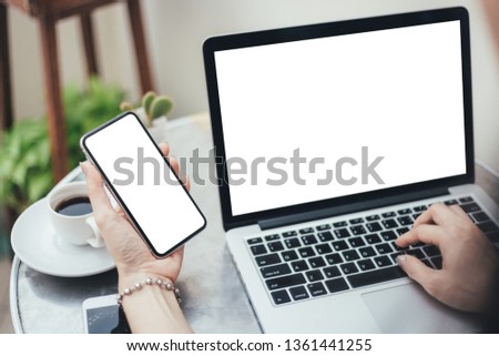 mockup image computer,cell phone blank screen for hand typing text,using laptop contact business searching information in workplace on desk at office.design creative work space on wooden desk
