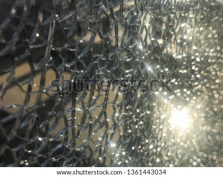 The texture of the broken cracked thick fragile broken sharp glass, triplex with shiny small fragments. The background.