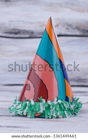 Clown paper hat on wooden background. Kids Birthday party cap with abstract pattern, vertical image.