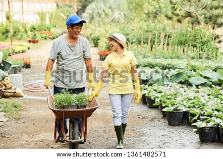 Cheerful gardeners with wheelbarrow