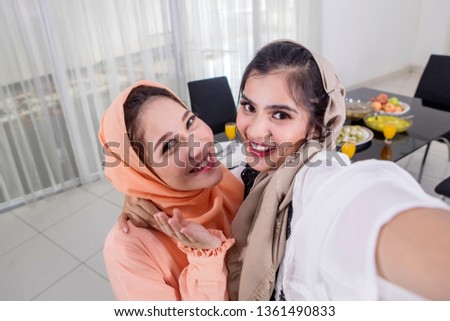 Picture of two Asian women taking selfie photos with happy expression before breaking the fast in the kitchen