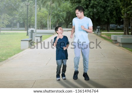 Picture of young father running with his son while exercising together in the park