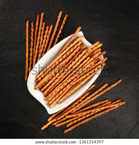 An overhead photo of salty sticks, shot from the top on a black background with copy space. Party snacks with a place for text