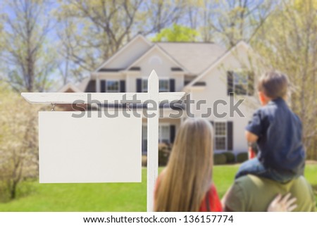 Mixed Race Young Family in Front of Blank Real Estate Sign and New House - Ready for Your Text.