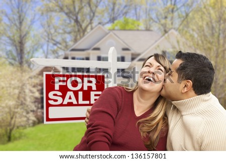 Happy Couple in Front of For Sale Real Estate Sign and New House.
