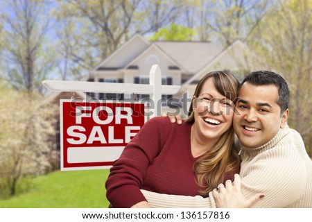 Happy Couple in Front of For Sale Real Estate Sign and New House.