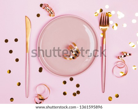 Pink plate, fork and knife and golden connfetti and ribbons on pink background, top view