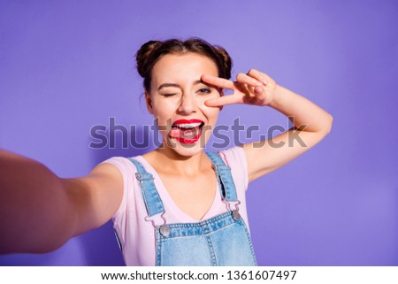Close up photo beautiful amazing she her lady two buns make take selfies show v-sign symbol near eye tongue out mouth wear casual t-shirt jeans denim overalls clothes isolated purple violet background