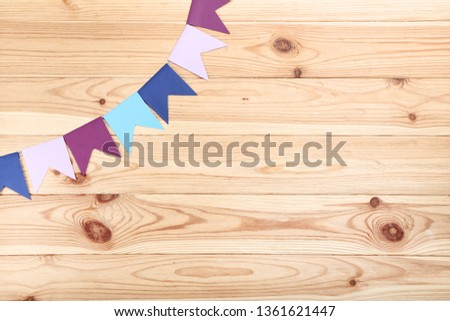 Colorful paper flags hanging on brown wooden background