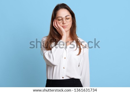 Portrait of exhausted sleeping businesswoman holding her head with closed eyes on right hand. Attractive young female enjoys short rest after hard tiresome working day. Cope space for advertisement.
