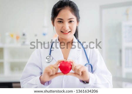 Beautiful smiley doctor hold red heart shape in hand at hospital, healthcare and medical concept.