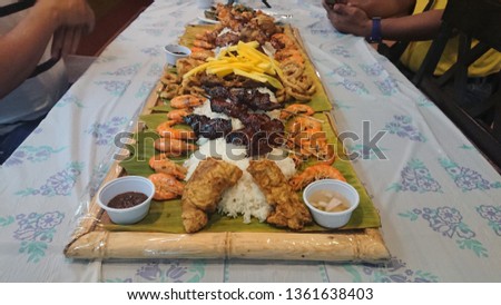 Boodle Fight Filipino traditional cuisine based on military practice of eating. Variety if food prepared on a bamboo and banana leaf and eaten using plastic as plate and bare hands or kamayan