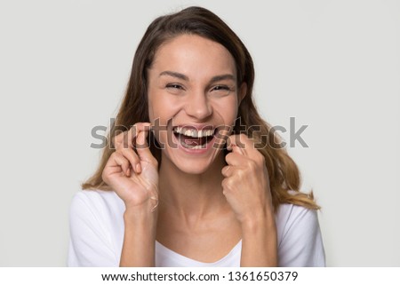 Beautiful smiling woman cleaning teeth with dental floss remove food between tooth preventing gingivitis and caries diseases, take care oral hygiene, concept image gray background studio shot portrait