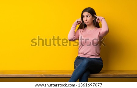 Young woman sitting on table having doubts and thinking