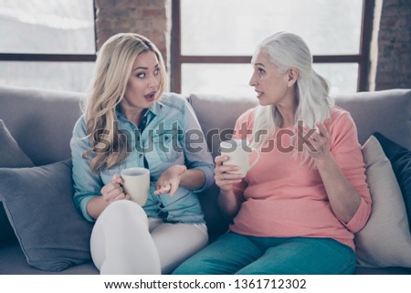 Close up photo two people she her ladies rumours mom granddaughter child grandmother hot beverage tea hands conversation tell speak say unbelievable secrets  sit comfy couch divan flat house indoors