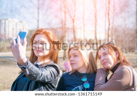 Girls smile and take a selfie together. Grimaces, wink and sign. Four girls, friends, smile and take a selfie together. The blonde girl raises her arms as a sign