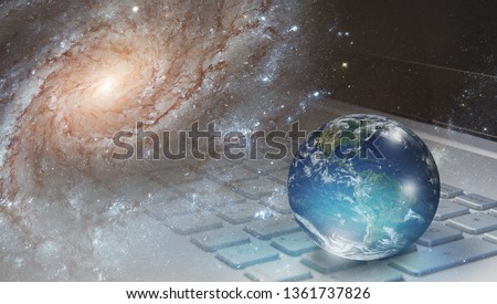 Glass globe on laptop keyboard with galaxy "Elements of this image furnished by NASA "  