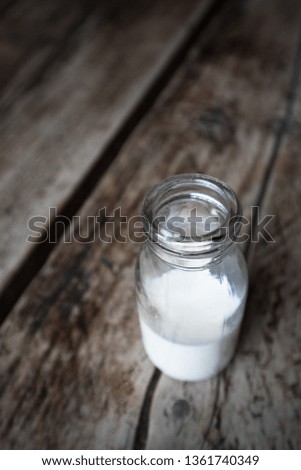 Miniature milk bottle with milk inside on a dark wood rustic table