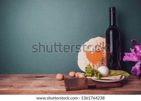 Pesach celebration concept. bottle of wine, book, matzo, egg, cider and lettuce