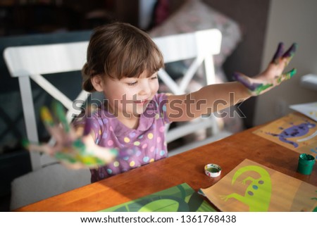 Cute little preschool gir having fun, showing her painted hands. Education, school, art and painitng concept