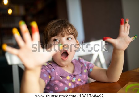 Cute little preschool gir having fun, showing her painted hands. Education, school, art and painitng concept