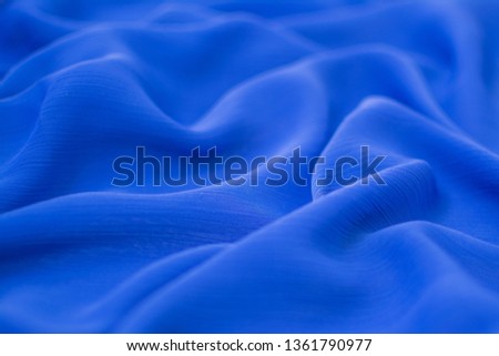 Silk crumpled fabric blue. View from above.
Textile and texture concept - close up of crumpled silk blue wavy fabric background