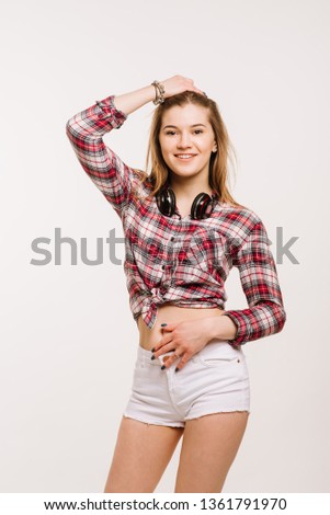 Happy young caucasian woman wearing shirt and shorts with headphones smiling and posing on the white background