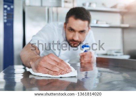 Hygienic precautions. Worker in restaurant kitchen cleaning down after service. Selective focus on his hand Royalty-Free Stock Photo #1361814020