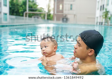 Father swimming with adorable little baby boy  in swimming pool