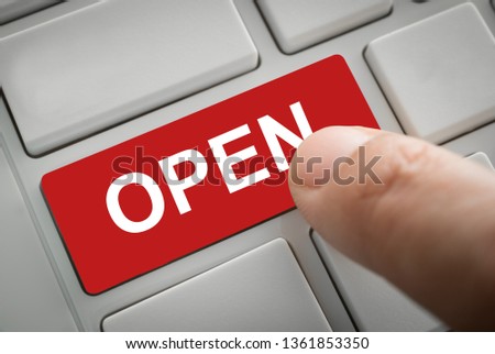 Businessman's fingers press in open button of a computer keyboard.