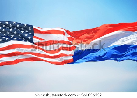 Flags of the USA and Luxembourg against the background of the blue sky