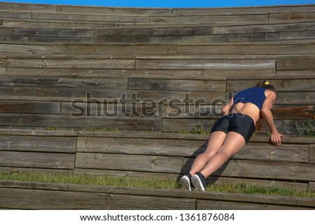 Woman making pushups  with wooden background, outdoors
