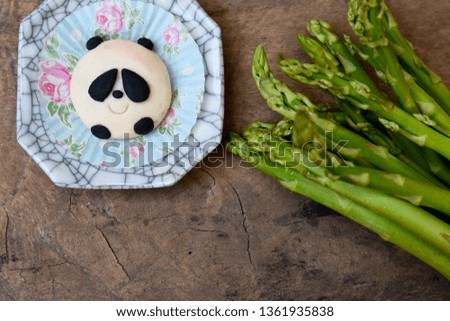 The panda-shaped cookie is on a plate with asparagus.
