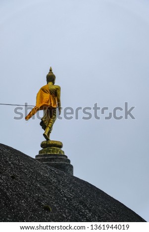 Buddha statue standing on the mountain with wind flow the yellow robe