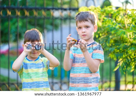 Two brother boy playing with modern spin top outdoors. Entertainment game for children. Top, triggered by a trigger. Kids demonstrate two different variants choosing which is better.
