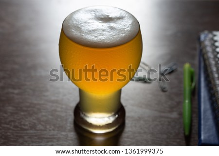 Glasses of beer and office accessories on wooden table, relax from work with cold beer concept