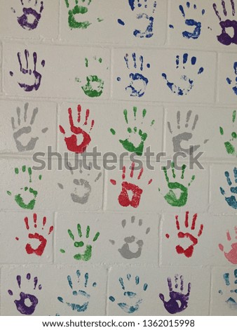 Multicolored handprints on a white brick wall