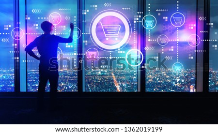 Online shopping theme with man writing on large windows high above a sprawling city at night