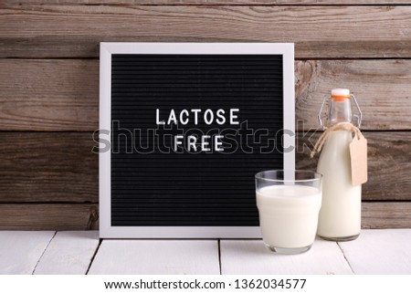 Allergic food concept. Milk bottle, milk glass and letter board with text LACTOSE FREE on wooden background. Royalty-Free Stock Photo #1362034577
