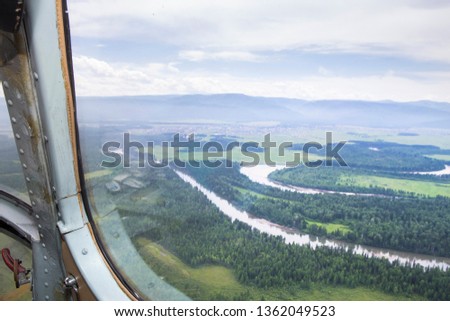 View from the cockpit of a flying helicopter over the Siberian taiga lakes and rivers.