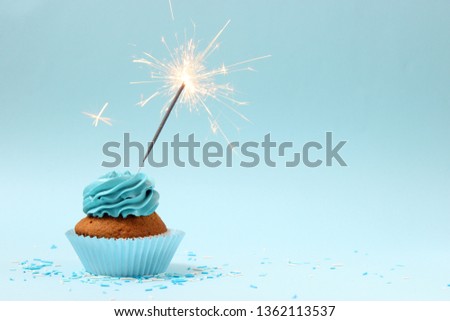 cupcake with sparkler on a colored background. Background for the holiday, birthday
