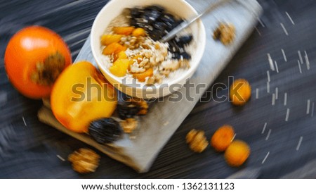 Blur in Motion Abstract Background of the Oatmeal with Persimmon, Prune, Dried Apricots, Walnut and Sesame on a Black Wooden Table.