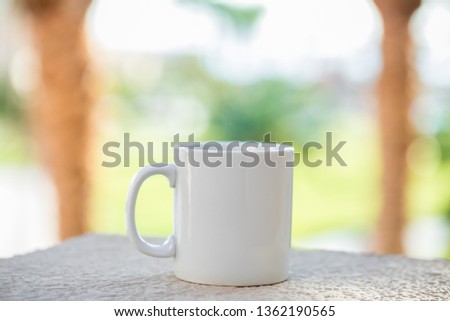 White blank mug for mock-up on the outside on the table in the garden 