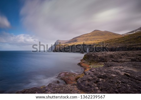 Scenic colorful landscape Picture on the coastline in faroese island Eysturoy, one of the Faroe islands with moutains, high cliffs, waterfall and rocky coast with huge wawes of north atlantic ocean.