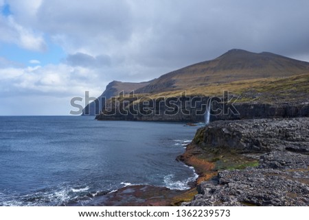 Scenic colorful landscape Picture on the coastline in faroese island Eysturoy, one of the Faroe islands with moutains, high cliffs, waterfall and rocky coast with huge wawes of north atlantic ocean.