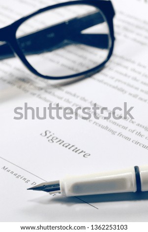Business contract paper with eyeglasses and fountain pen.